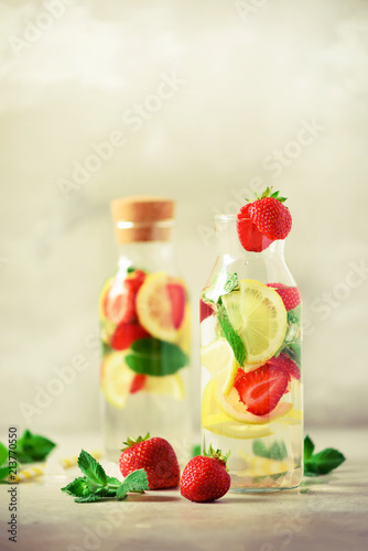 Strawberry detox water with mint, lemon on grey background. Citrus lemonade. Summer fruit infused water. Copy space