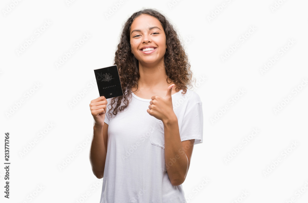 Young hispanic woman holding passport of Australia happy with big smile doing ok sign, thumb up with fingers, excellent sign Young hispanic woman holding passport of Australia happy with big smile doing ok sign, thumb up with fingers, excellent sign