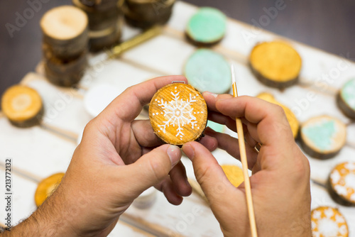 Creating a Christmas-tree toys handmade. Christmas handmade toys on New Year tree. Hands of master creating a Christmas tree made of wood toys. Christmas decorations hand-painted