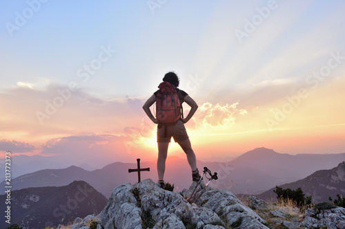 hiking woman with hands on her waist looking at sunset