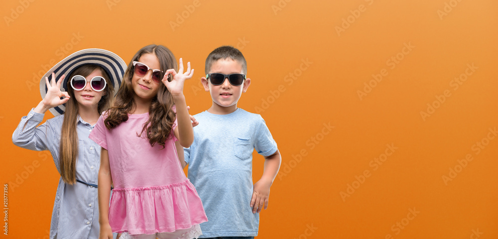 Group of boy and girls kids over orange background doing ok sign with fingers, excellent symbol Group of boy and girls kids over orange background doing ok sign with fingers, excellent symbol