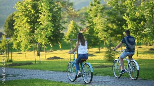Happy couple riding a bicycle in the park. summer time. sunset
