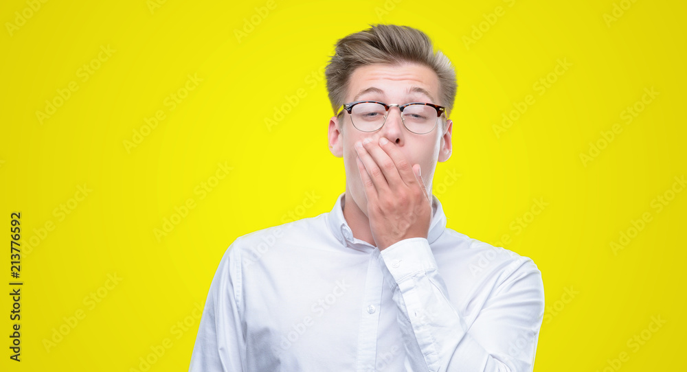 Young handsome blond man bored yawning tired covering mouth with hand. Restless and sleepiness. Young handsome blond man bored yawning tired covering mouth with hand. Restless and sleepiness.