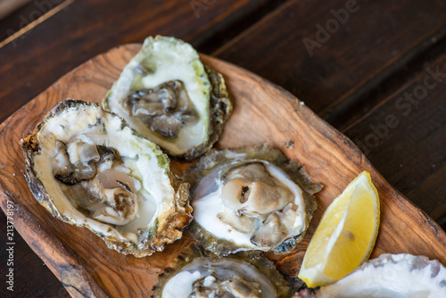 Oysters with lemon on wooden plate.