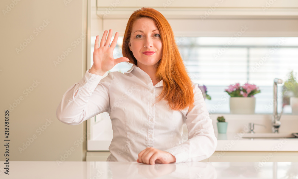 Redhead woman at kitchen showing and pointing up with fingers number five while smiling confident and happy. Redhead woman at kitchen showing and pointing up with fingers number five while smiling confident and happy.