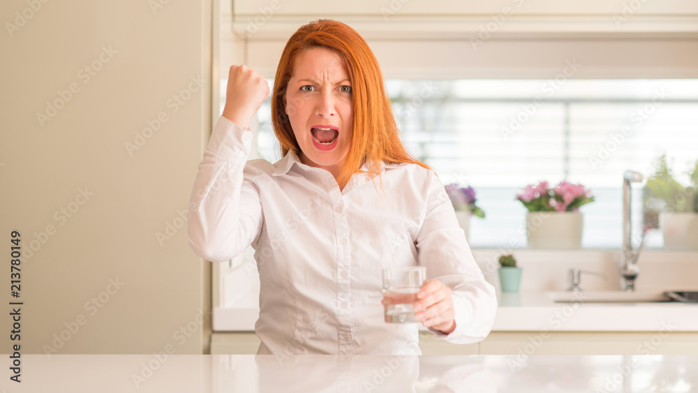 Thirsty redhead woman and glass of water annoyed and frustrated shouting with anger, crazy and yelling with raised hand, anger concept