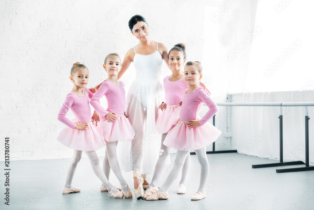 ballet teacher with cute little ballerinas smiling at camera in ballet school ballet teacher with cute little ballerinas smiling at camera in ballet school