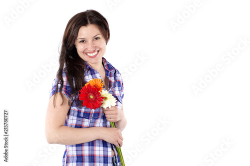 Smiling young woman in a plaid shirt with gerbera flowers isolated on white