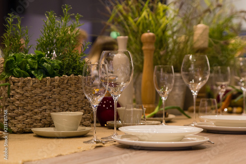 Empty wine glasses, cups and basket with greenery photo