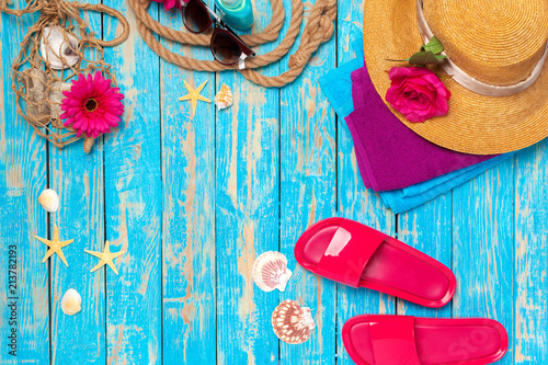 Bright composition of female beach accessories on blue wooden background
