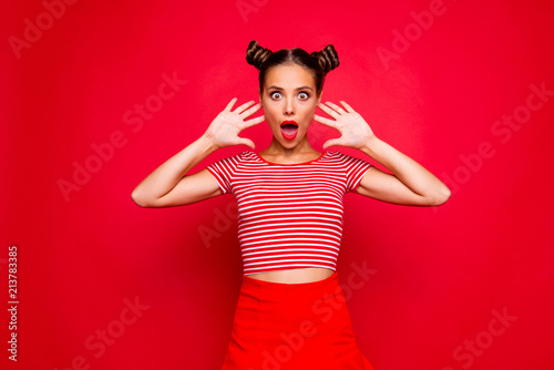 Portrait of young gorgeous and shocked girl with brown eyes and red lipstick on the mouse look at the camera with her fingers spread wide. Concept of advertising isolated on red background