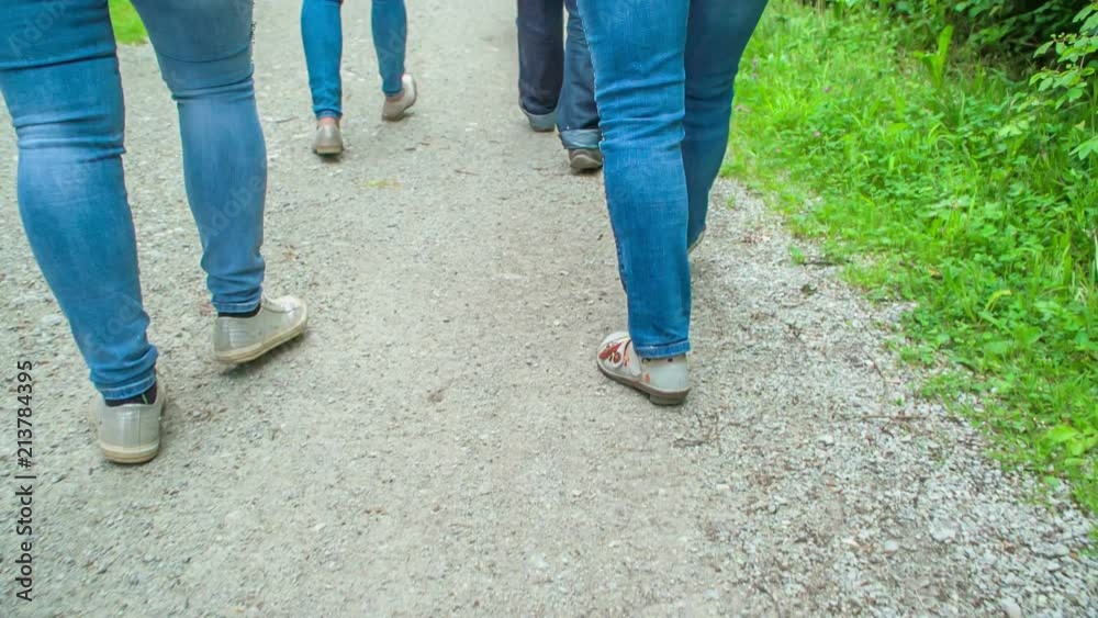 Four people are walking on a path in the middle of nature. We can only see their feet. Four people are walking on a path in the middle of nature. We can only see their feet.