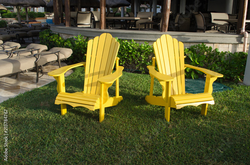 Yellow chairs in park. Grass, poolside © InfoDaksh