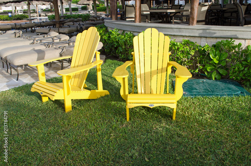 Yellow chairs in park. Grass, poolside © InfoDaksh