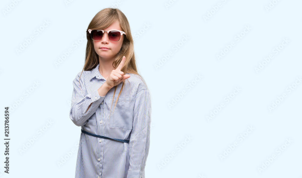 Young blonde toddler wearing blue shirt very happy pointing with hand and finger to the side Young blonde toddler wearing blue shirt very happy pointing with hand and finger to the side