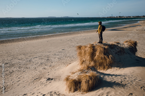 Young traveler man walking on the beach and enjoying wonderful panoramic view of blue cold sea. Sunny winter day. Norway photo