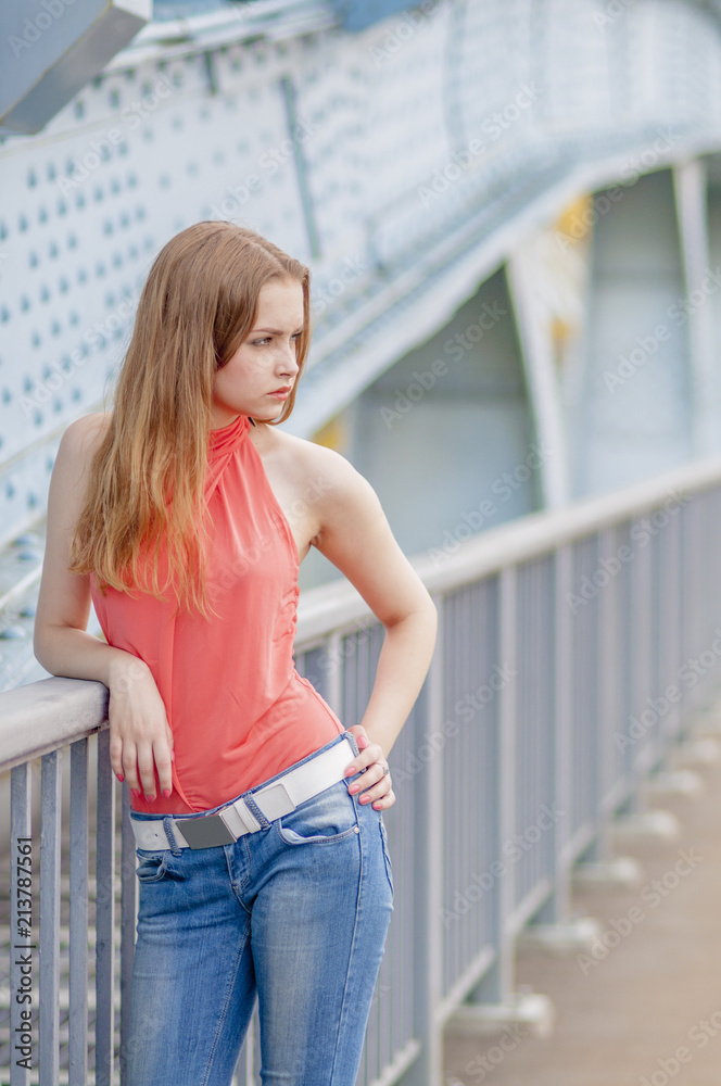 Beautiful young girl with long hair dreamily waiting at the bridge
