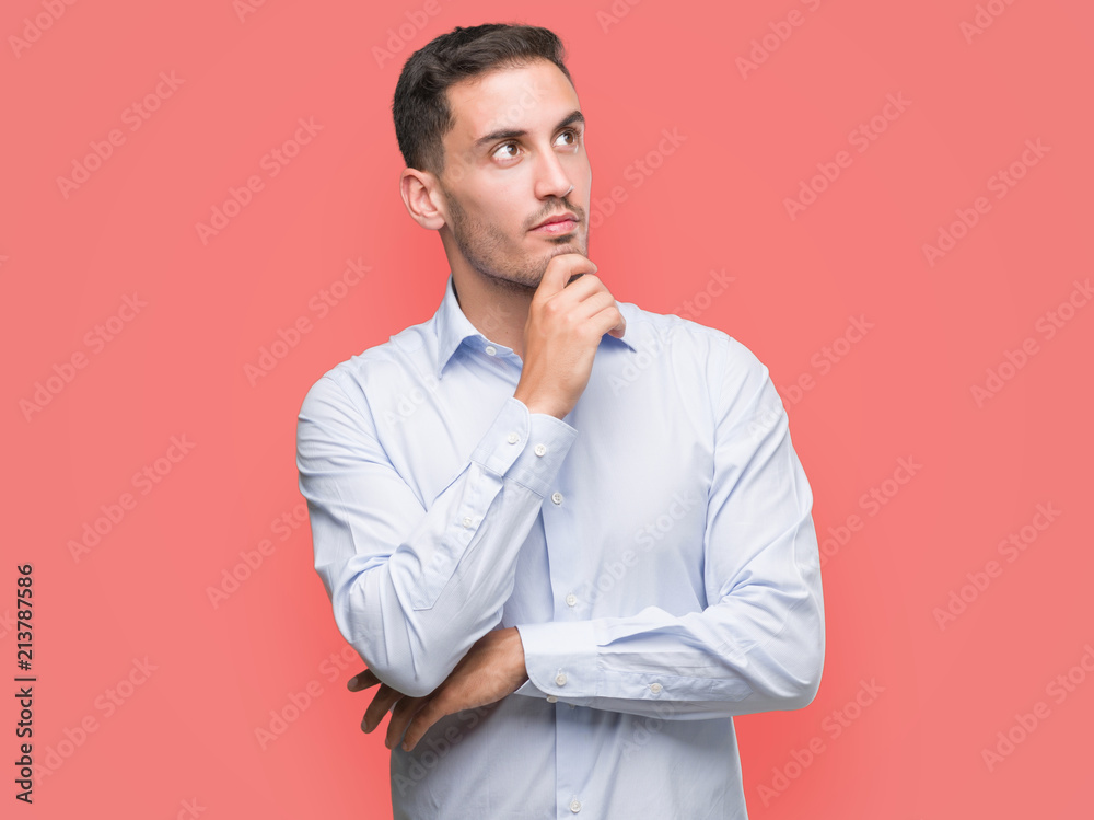 Handsome young businessman with hand on chin thinking about question, pensive expression. Smiling with thoughtful face. Doubt concept. Handsome young businessman with hand on chin thinking about question, pensive expression. Smiling with thoughtful face. Doubt concept.