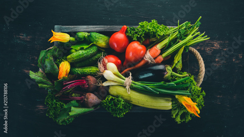 A set of fresh vegetables in a wooden box. On a wooden background. Top view. Copy space.