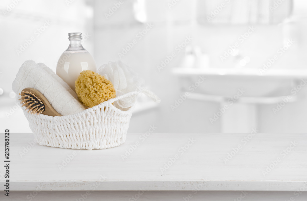 White basket with spa products on wooden table inside bathroom White basket with spa products on wooden table inside bathroom