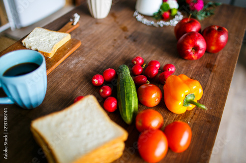 Summer breakfast, radish, tomatoes, cucumber and pepper on wooden board. Coffee cup with toast