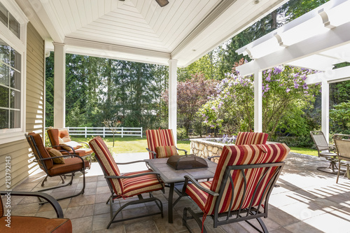 Spacious covered deck patio with table and red chairs.