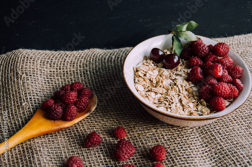 Delicious, healthy breakfast.Porridge with berries.Ecofriendly.Oatmeal porridge with raspberries and cherries.The idea for breakfast on black background. Natural, dietary food.Good morning. Life style