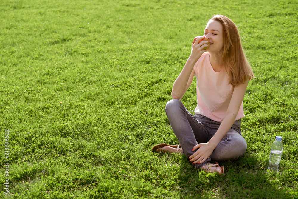 Fototapeta premium girl on the lawn eating an Apple