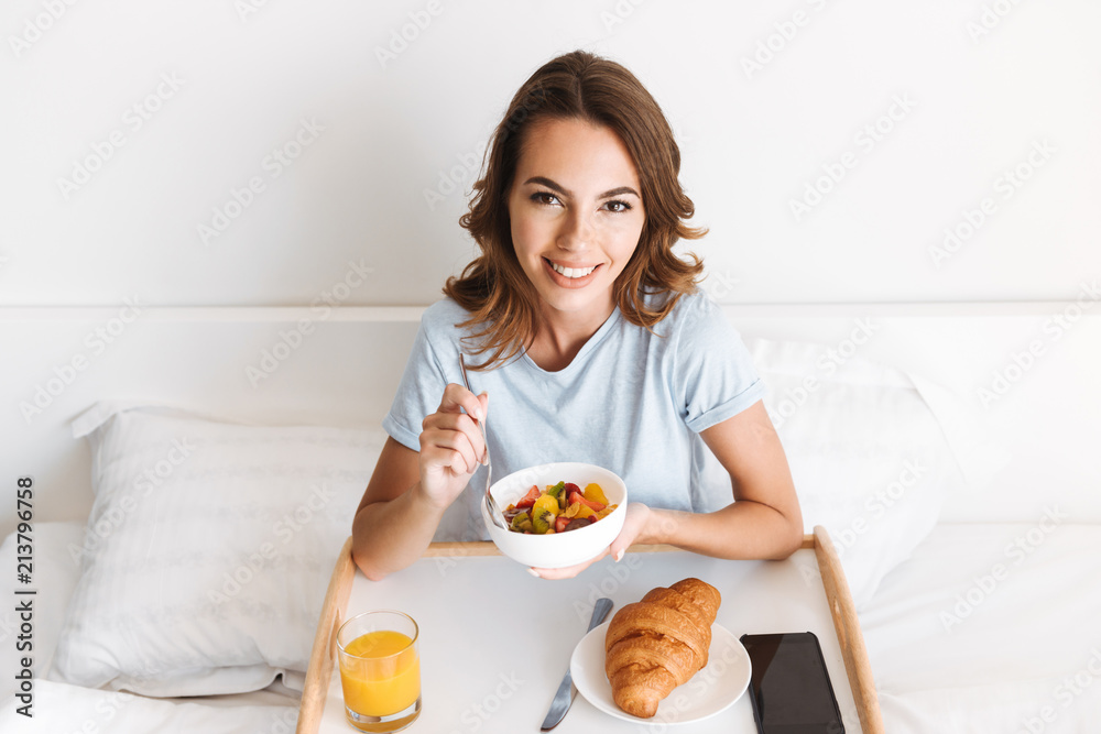 Smiling young woman having healthy breakfast on a tray Smiling young woman having healthy breakfast on a tray