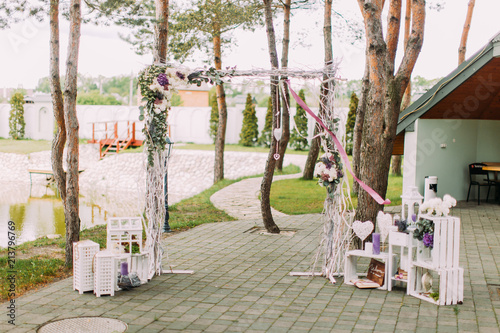 The open air wedding concept of the vintage wedding arch decorated with flowers and surrounded by wooden boxes and candle stands. photo