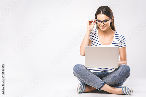 Business concept. Portrait of happy woman in casual sitting on floor in lotus pose and holding laptop isolated over white background.