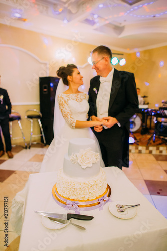 The white marzipan cake with flowers at the background of the happy newlyweds. photo