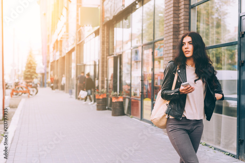 Obraz na plátne Young pretty latin woman walking near shops in city centre