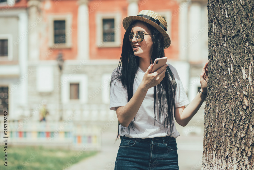 Fototapeta premium Pretty brunette woman internet blogger talking by smartphone in old city