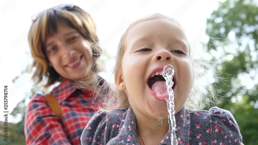 Little child girl portrait face funny drink lap up pure water from drinking fountain slow motion