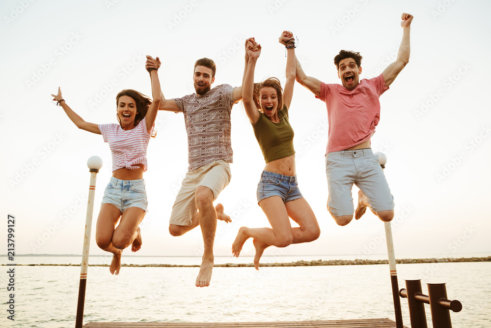 Friends loving couples jumping outdoors on the beach. Friends loving couples jumping outdoors on the beach.