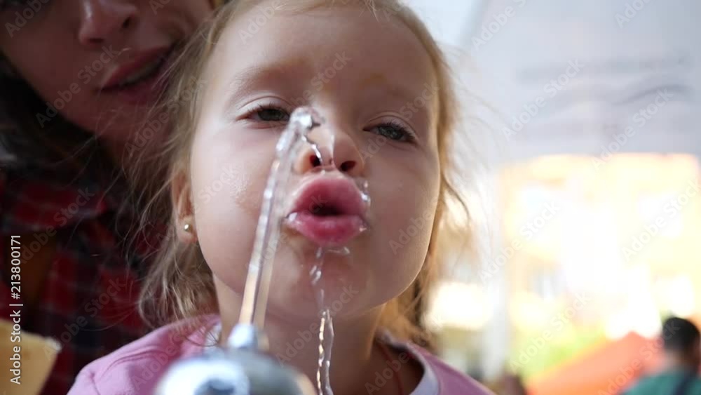 Little girl face closeup catch drink water jet from street drinking fountain in slow motion