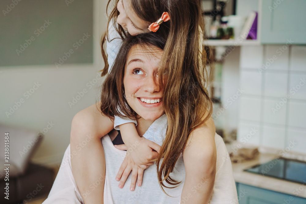 Naklejka premium beautiful little daughter piggybacking on her happy mother