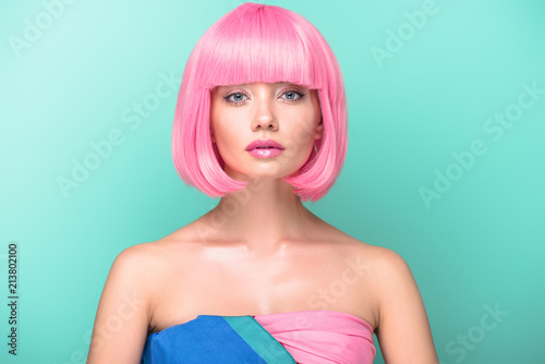 young woman with pink bob cut looking at camera isolated on turquoise