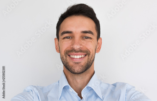Fotografie Closeup portrait of happy handsome young male smiling with healhty toothy smile looking at the camera, making self portrait