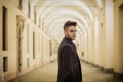 Handsome young man under cloisters in Italian city center, Turin, at night