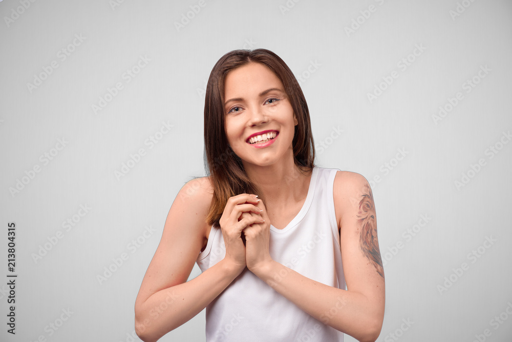 Studio shot of young European female with pleased expression, looks directly into camera, admires something in front, isolated over white background. People, facial expressions, lifestyle concept Studio shot of young European female with pleased expression, looks directly into camera, admires something in front, isolated over white background. People, facial expressions, lifestyle concept