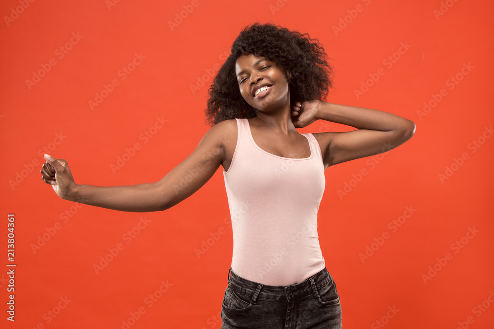The happy business woman standing and smiling against red background.