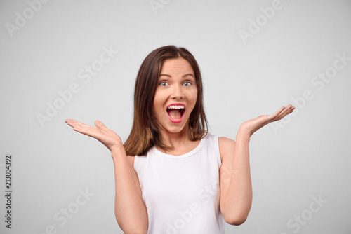 Wow. Beautiful female half-length front portrait isolated on white studio backgroud. Young emotional surprised woman standing with open mouth. Human emotions, facial expression concept