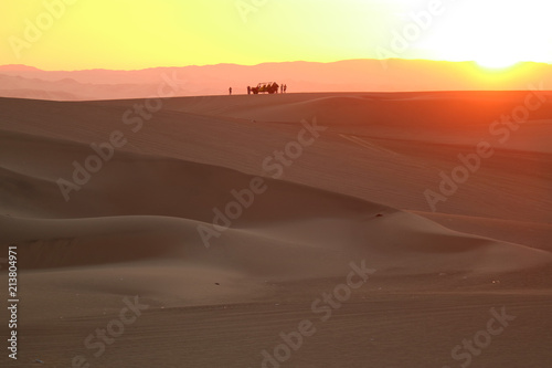 Gorgeous color layer of sunset over the sand dune of Huacachina desert with the silhouette of dune baggy and people, Ica, Peru 