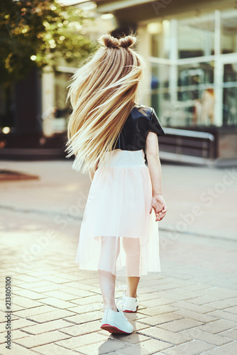 Lifestyle portrait of stylish little girl teenager. Beautiful child, wearing black jacket, pink skirt. Beautiful long hair.