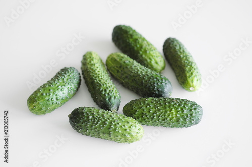 A bunch of several gherkin cucumbers lie on a white background.