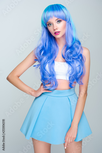 cropped shot of young woman with curly bright blue hair isolated on grey