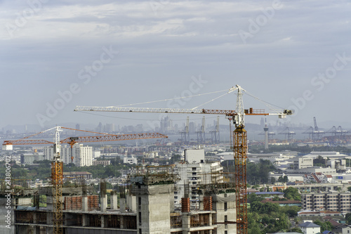 Industrial construction cranes and building on city background