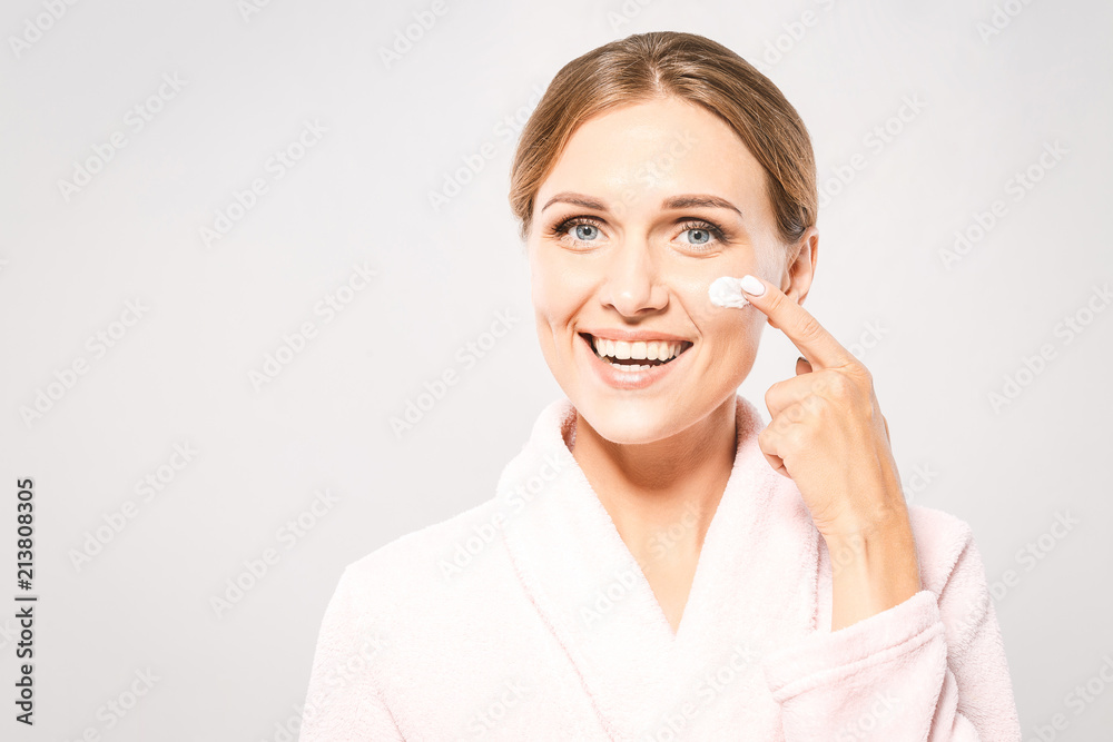 Portrait of young beautiful woman smiling while taking some facial cream isolated on white background with copy space. Portrait of young beautiful woman smiling while taking some facial cream isolated on white background with copy space.